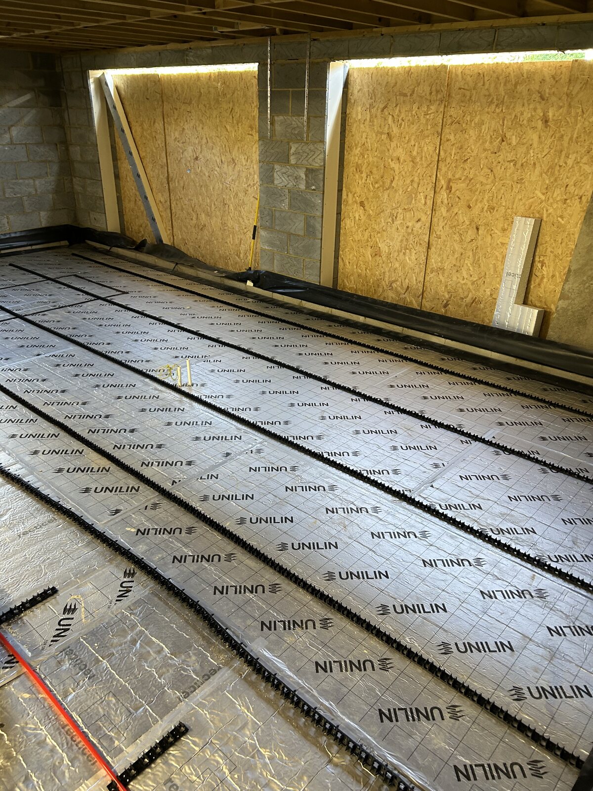 Pipe fixing rails installed across the insulated floor in the Wadhurst extension