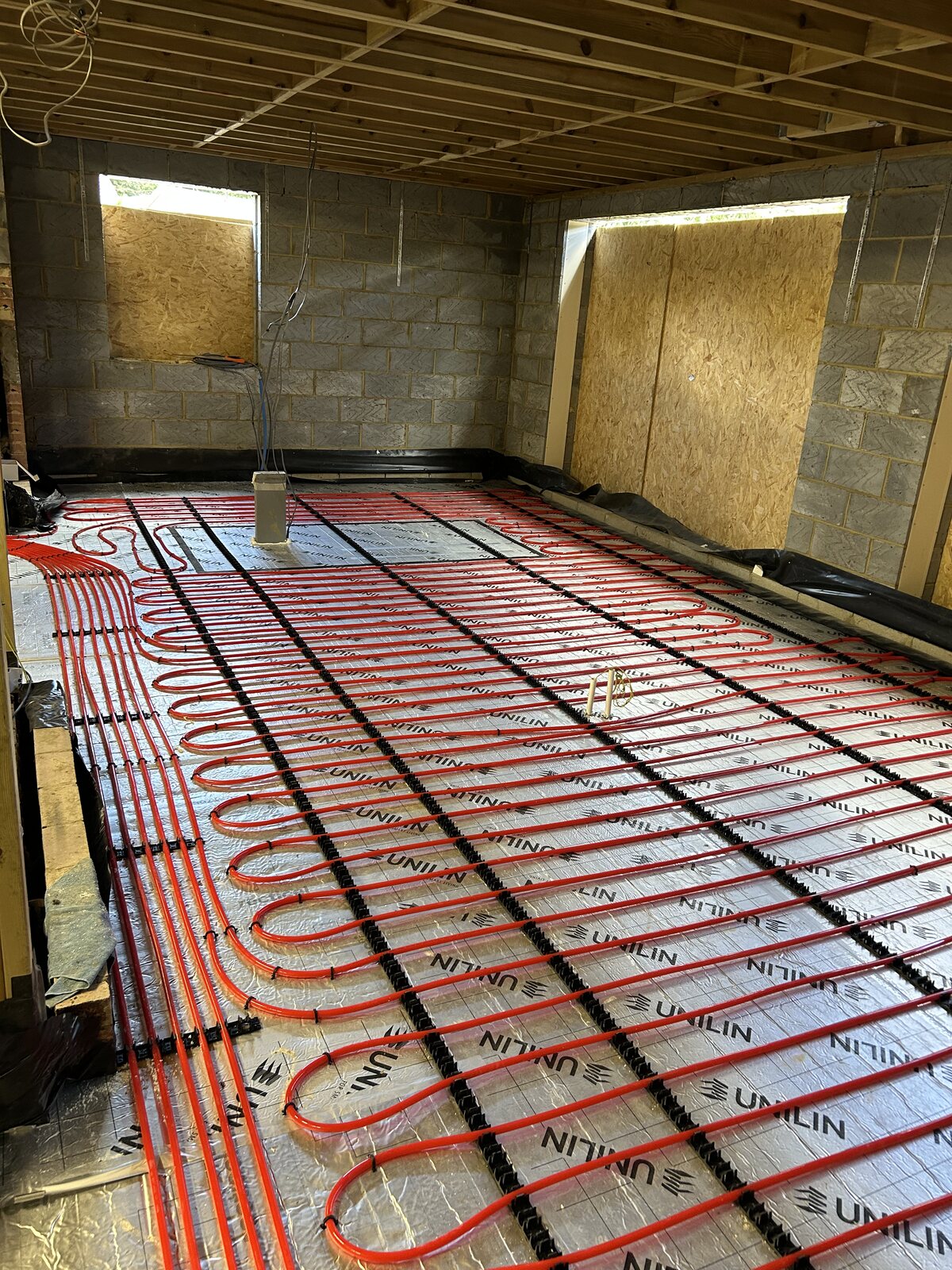 Red wet underfloor heating pipework laid across the insulated extension floor